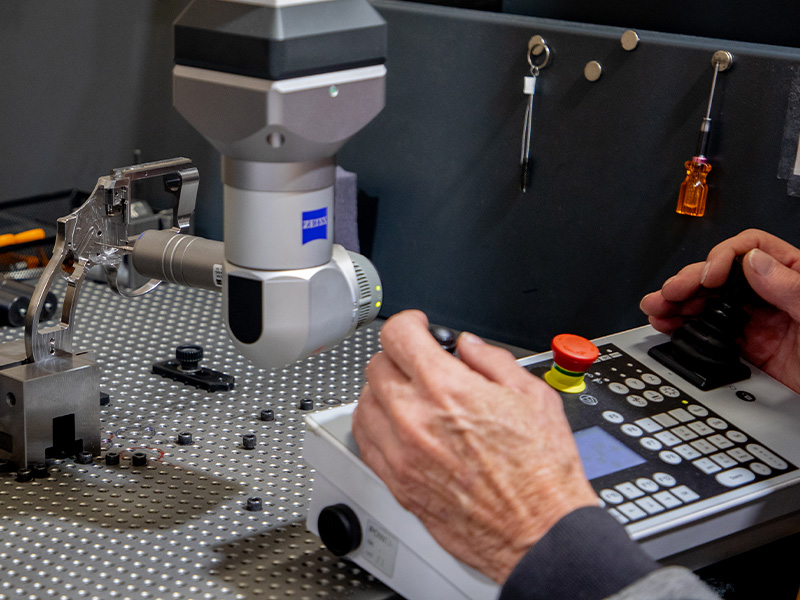 A technician operating a coordinate measuring machine to inspect a metal component