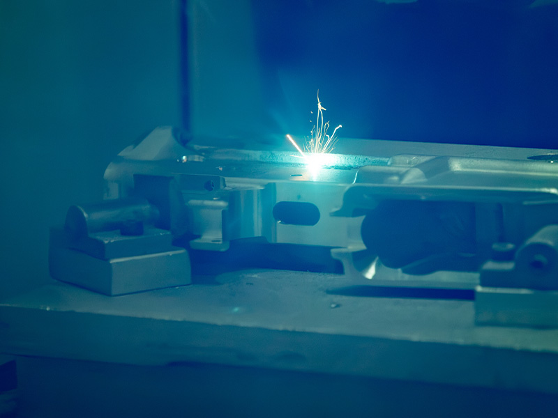 A laser engraving a metal component in a production fixture