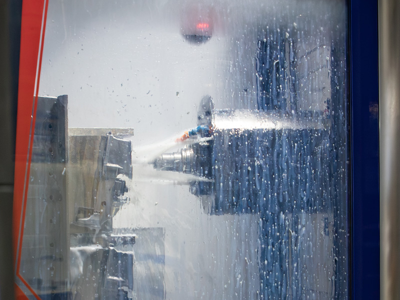 Coolant spraying inside a CNC machining enclosure at Diamondback CNC